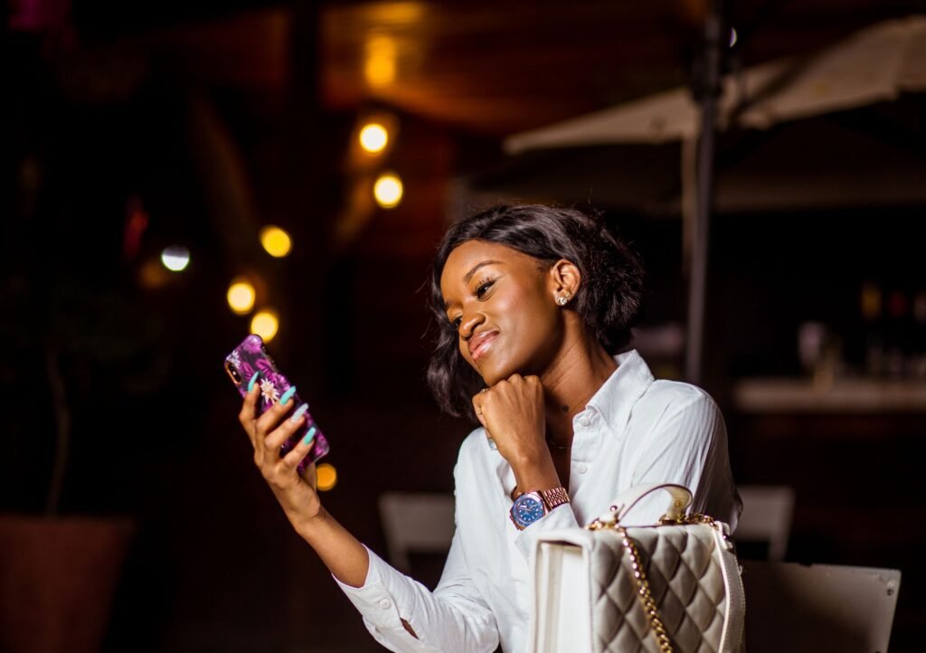 A woman smiles as she looks at her smartphone in the evening.
