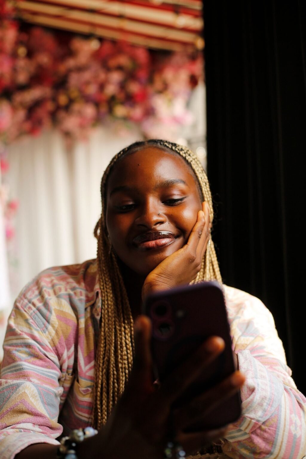 A young woman smiles as she reads something on her smartphone in an Abuja café.