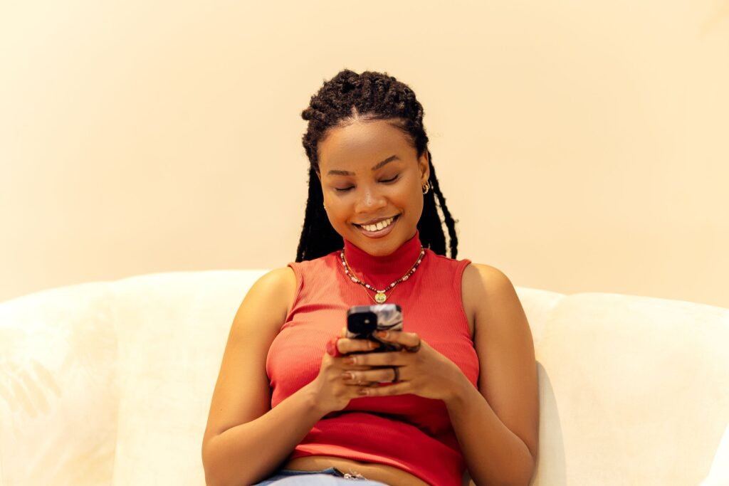 A smiling young woman in Lagos types on her phone.